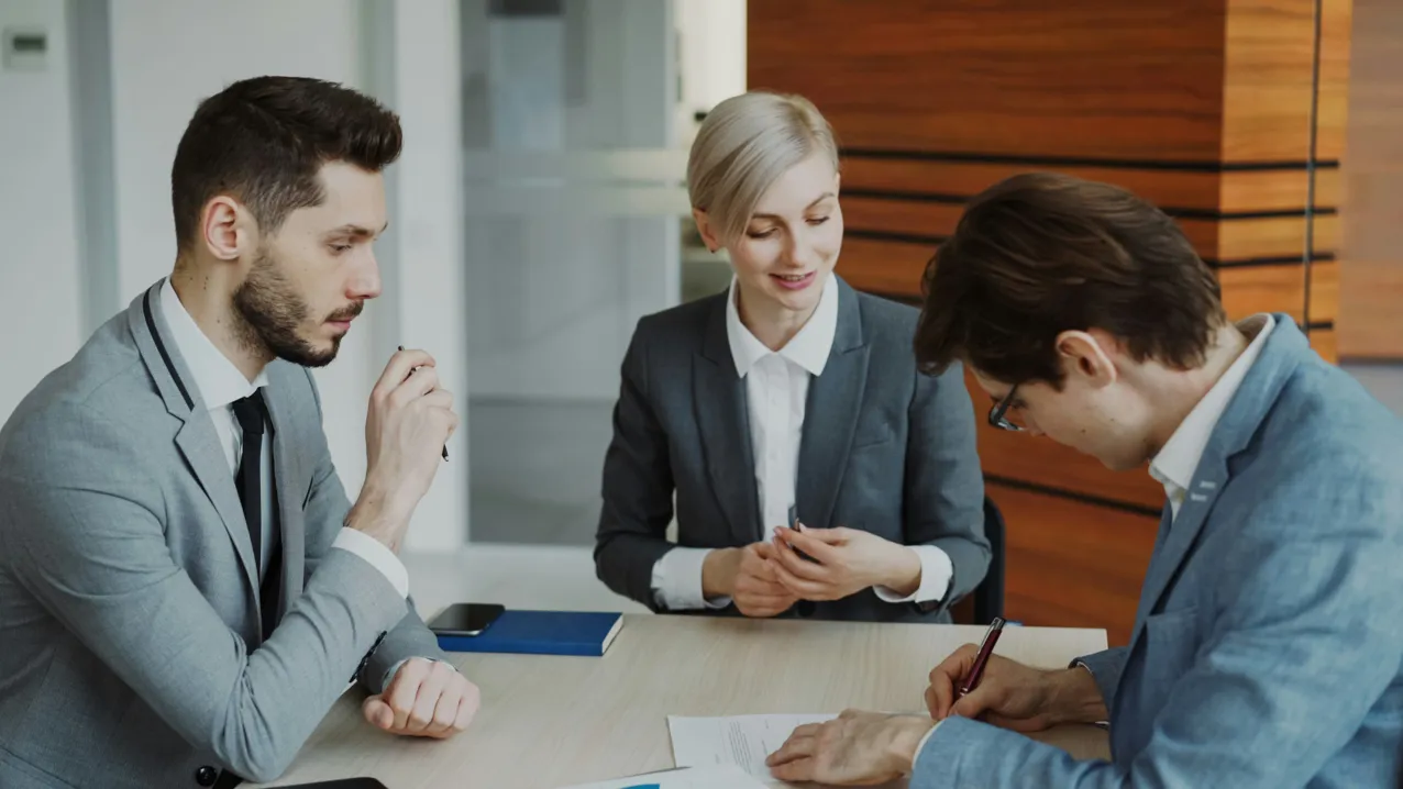 Business professionals reviewing and signing a contract at a conference table