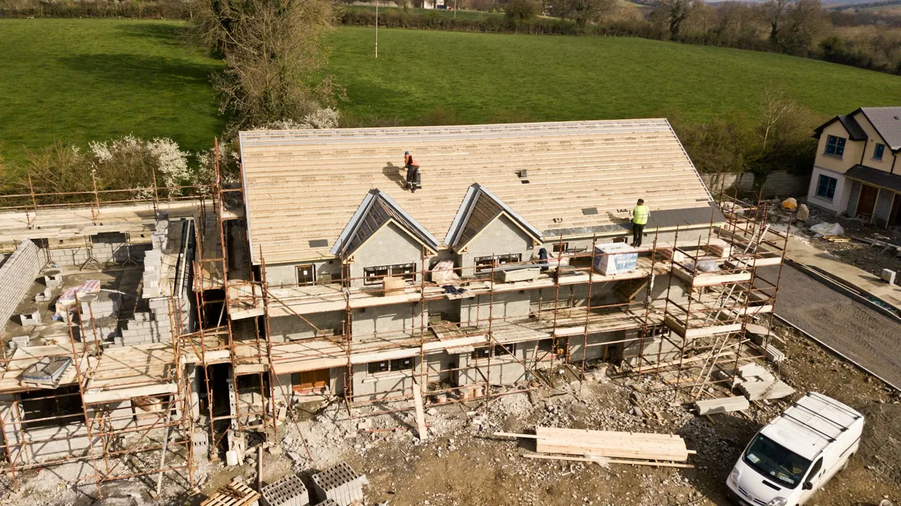 Roofers installing shingles with a nail gun on a residential roof