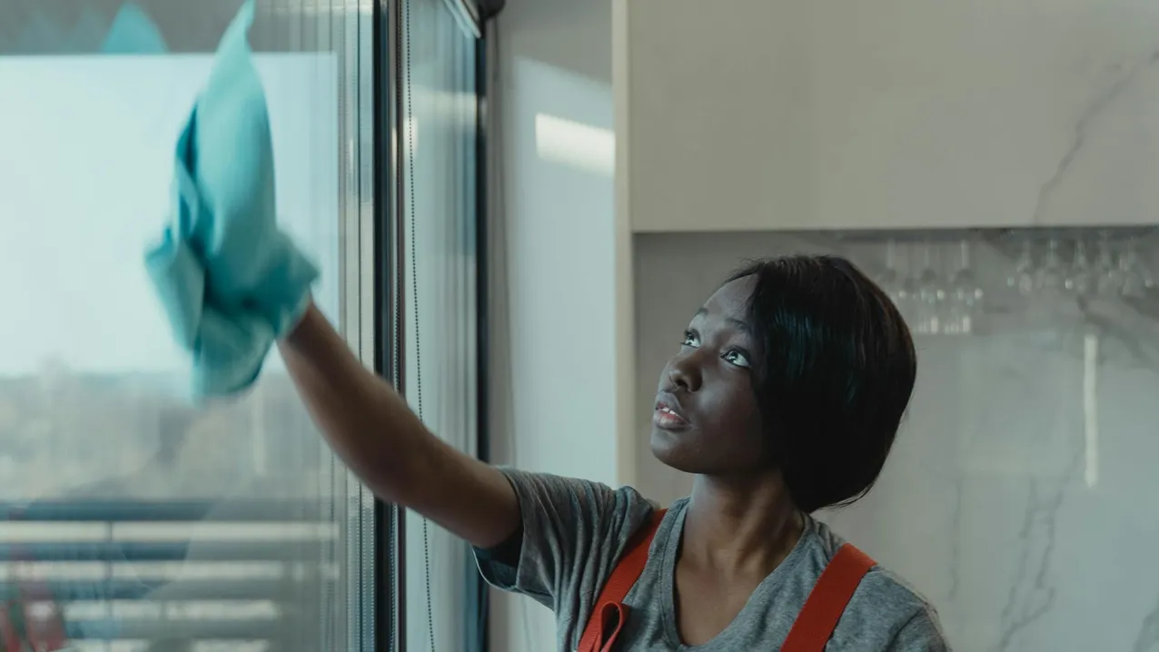 Window cleaning technician with squeegee on residential building exterior