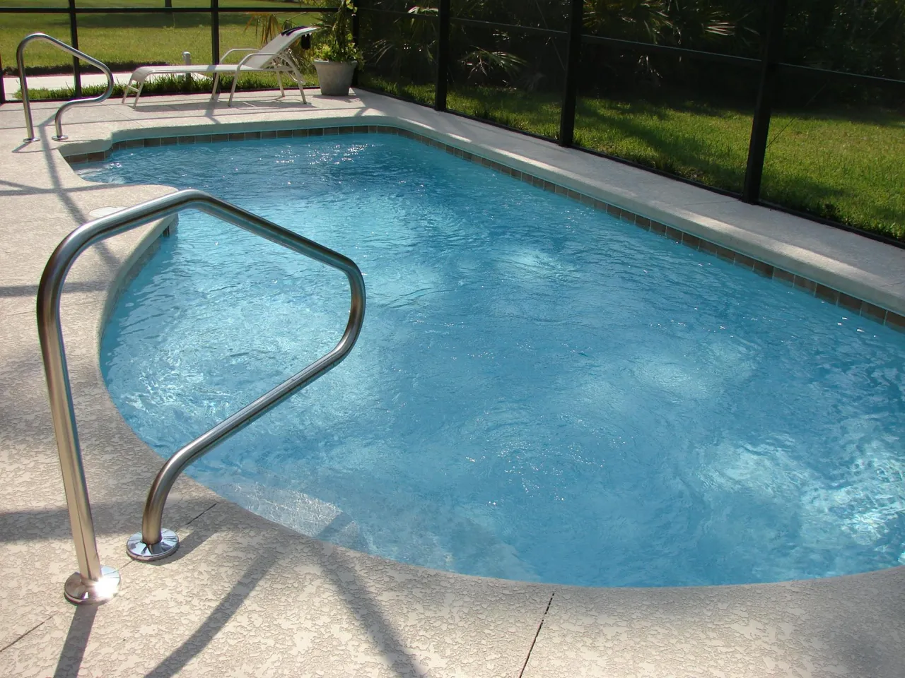 Pool service technician skimming a residential swimming pool